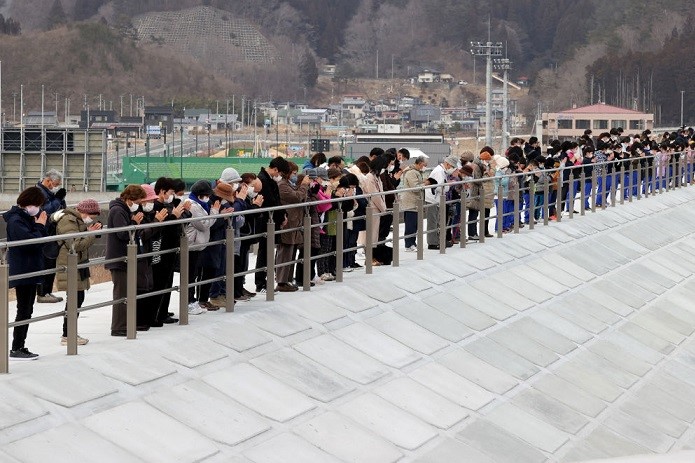 2022年3月11日，日本岩手縣宮古鎮，人們在為3.11東日本大地震死去的人默默祈禱。（STR/JIJI PRESS/AFP via Getty Images）