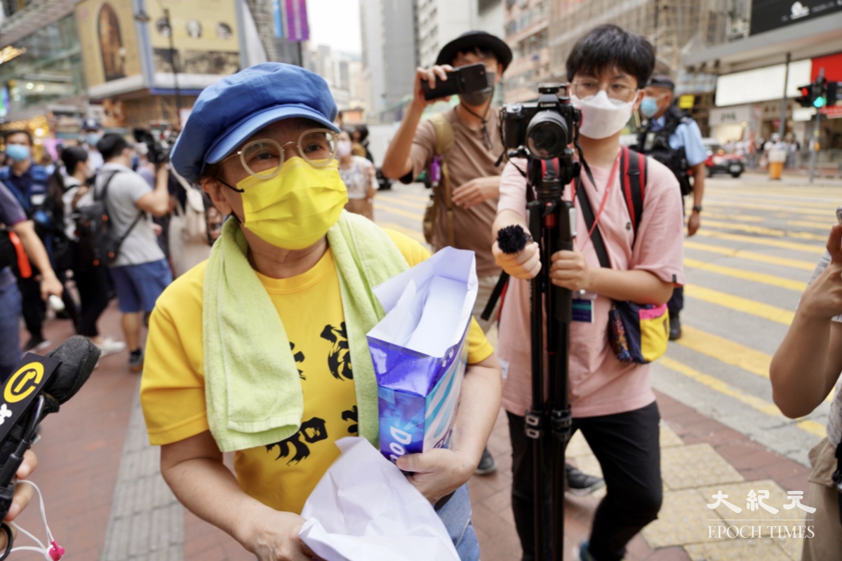 有穿著「香港加油」黃色衫女士在銅鑼灣派發A4白色紙張，被警方截查。（余鋼/大紀元）