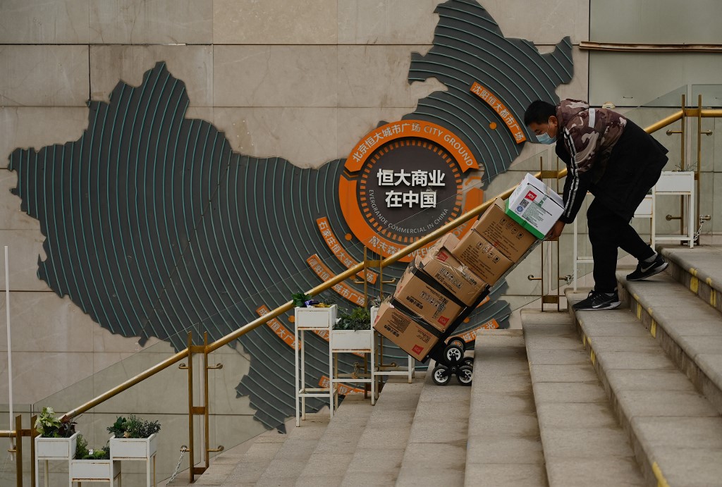 一家離岸公司目前在起訴中國地產龍頭企業恒大集團，向香港高等法院提請將其清盤。圖為2021年12月，北京一名工人推著一輛手推車經過恒大集團在中國的營運標識。（Noel Celis / AFP）
