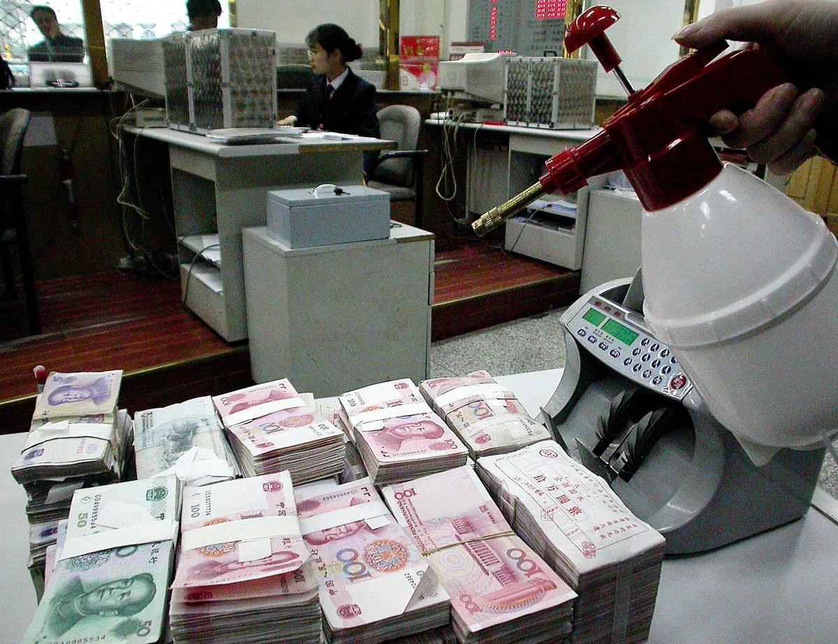 2003年4月24日，中國SARS爆發期間，南京一家銀行的工作人員在給人民幣消毒。（AFP）