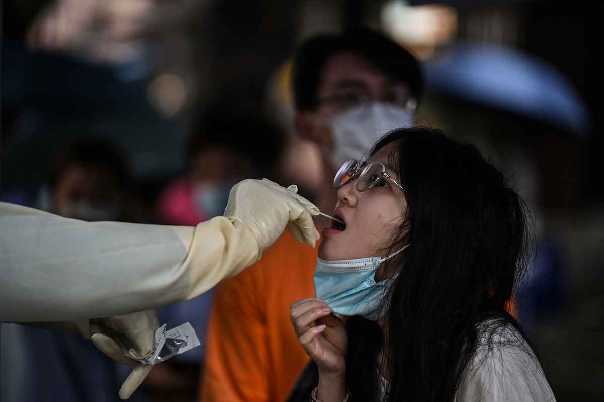 2022年6月13日，在上海靜安區，一名衛生工作者從一名婦女身上採集拭子樣本以檢測 Covid-19 冠狀病毒。（Hector RETAMAL / AFP）