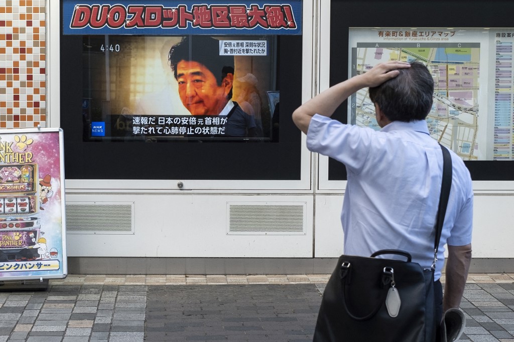日股在安倍遇襲後聞訊跳水。圖為日本民眾在觀看今天的新聞。（CHARLY TRIBALLEAU / AFP）