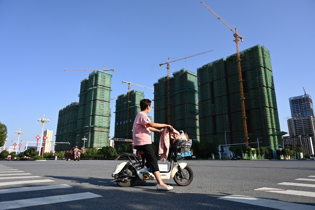 近日，爛尾樓停貸潮在中國全國範圍內急速蔓延，恒大名下的爛尾樓幾乎佔了一半。圖為2021年9月，河南駐馬店，一名女子騎車經過恒大樓盤施工現場。（JADE GAO / AFP）