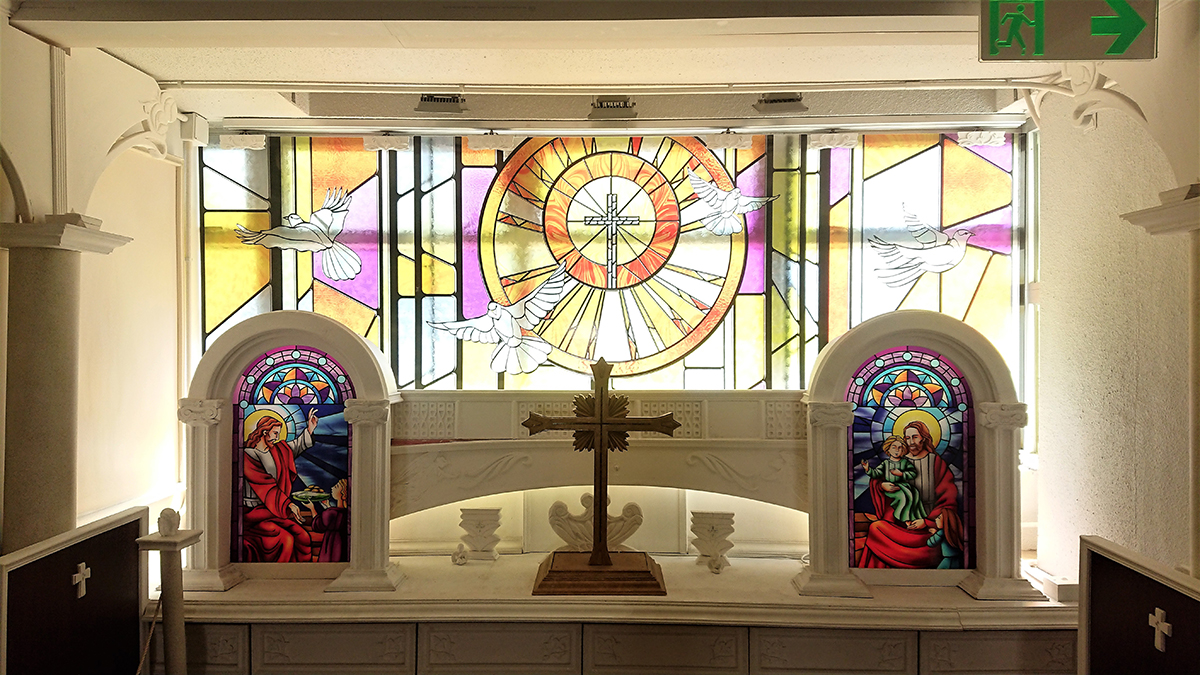 學校走廊盡頭的十字架及彩繪玻璃聖像。（鄺嘉仕提供）