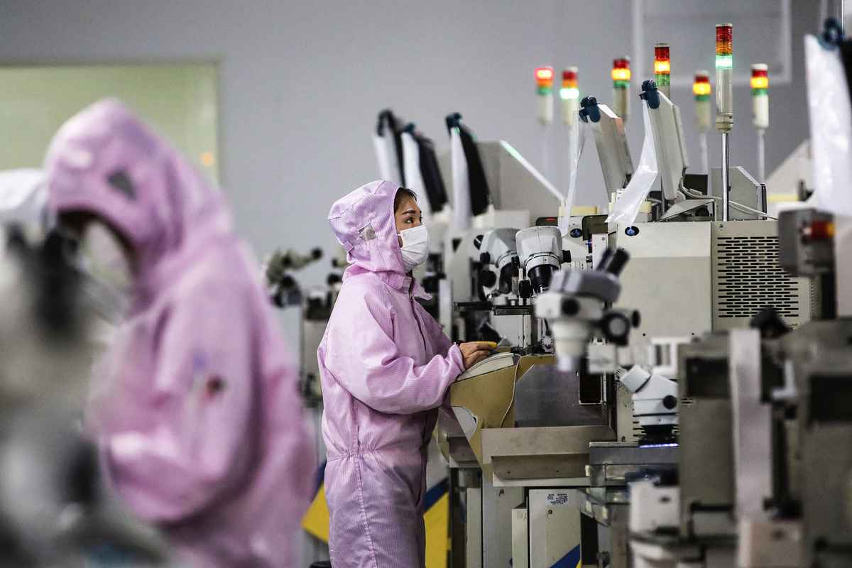 2020 年 2 月 16 日，工人們戴著口罩，穿著防護服，在江蘇省泗洪的一條智能晶片生產線上工作。（STR /AFP）