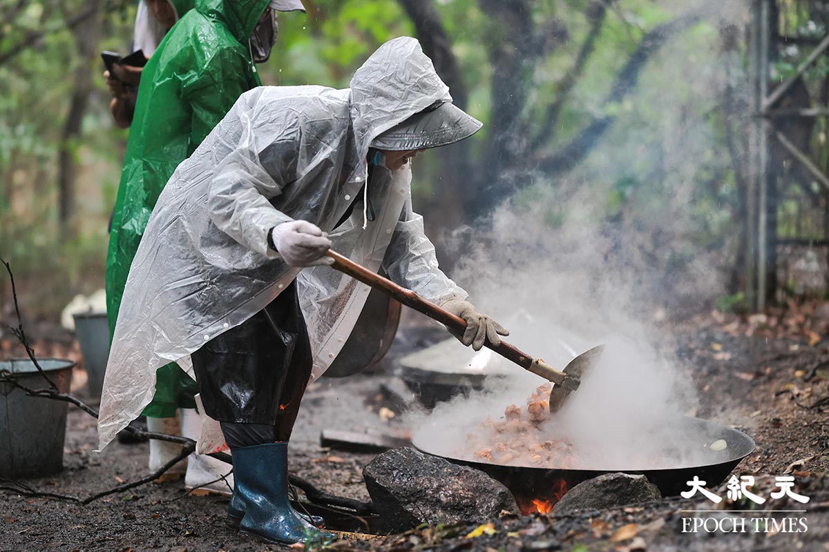 煮山頭期間遇上天雨，工人們一度穿上雨衣煮食。（陳仲明／大紀元）