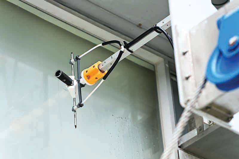 「外牆高空工作線控機械人」能模仿工人在外牆以雨刮抹窗及控制滾筒塗漆。（宋碧龍／大紀元）