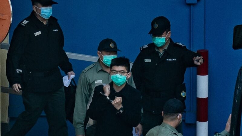在囚兩年的前香港眾志秘書長黃之鋒，在其facebook專頁透過友人發文，引歌詞說「我未有垮掉」。圖為2020年12月18日， 黃之鋒（中，戴手銬者）在荔枝角收押所。資料圖片。（Anthony Kwan/Getty Images）