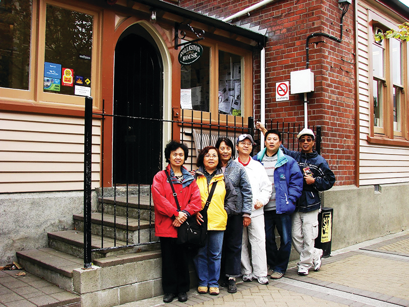 周素子與朋友在紐西蘭基督城拍攝於下榻的旅社前。（作者提供）