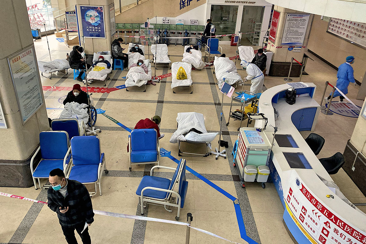 2022年12月23日，重慶市第五人民醫院大廳的封鎖區前，Covid-19患者躺在病床上。(Noel CELIS / AFP)