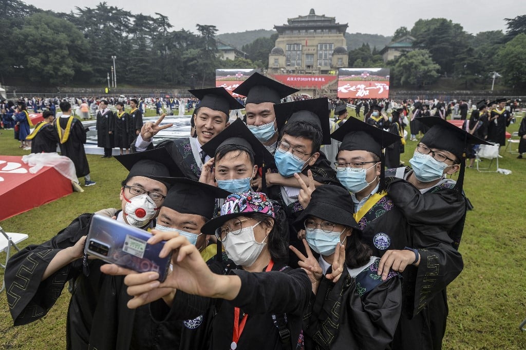 中國十多個省份近期相繼發布通知，明確不再增設新大學。有學者表示，中國人口下降造成生源大幅減縮。圖為2020年6月，湖北武漢大學的畢業典禮上，畢業生戴著口罩自拍。（STR / AFP）