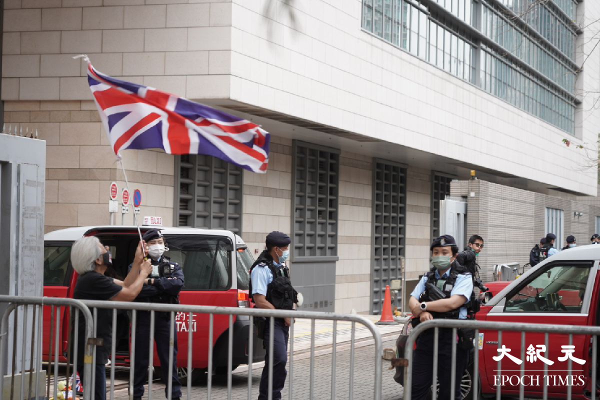 王婆婆在囚車入口處揮動英國國旗，被大批警員包圍。（余鋼／大紀元)