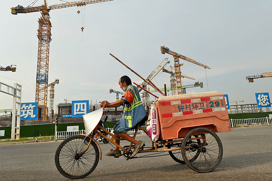 2021年9月17日，一名工人在廣州市正在建設的足球場前路過。(Noel Celis / AFP)