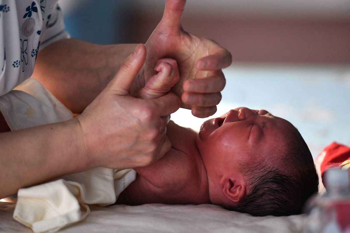 2023 年 1 月 17 日，一名護士在中國東部安徽省阜陽市的一家醫院照顧一名新生兒。(AFP)