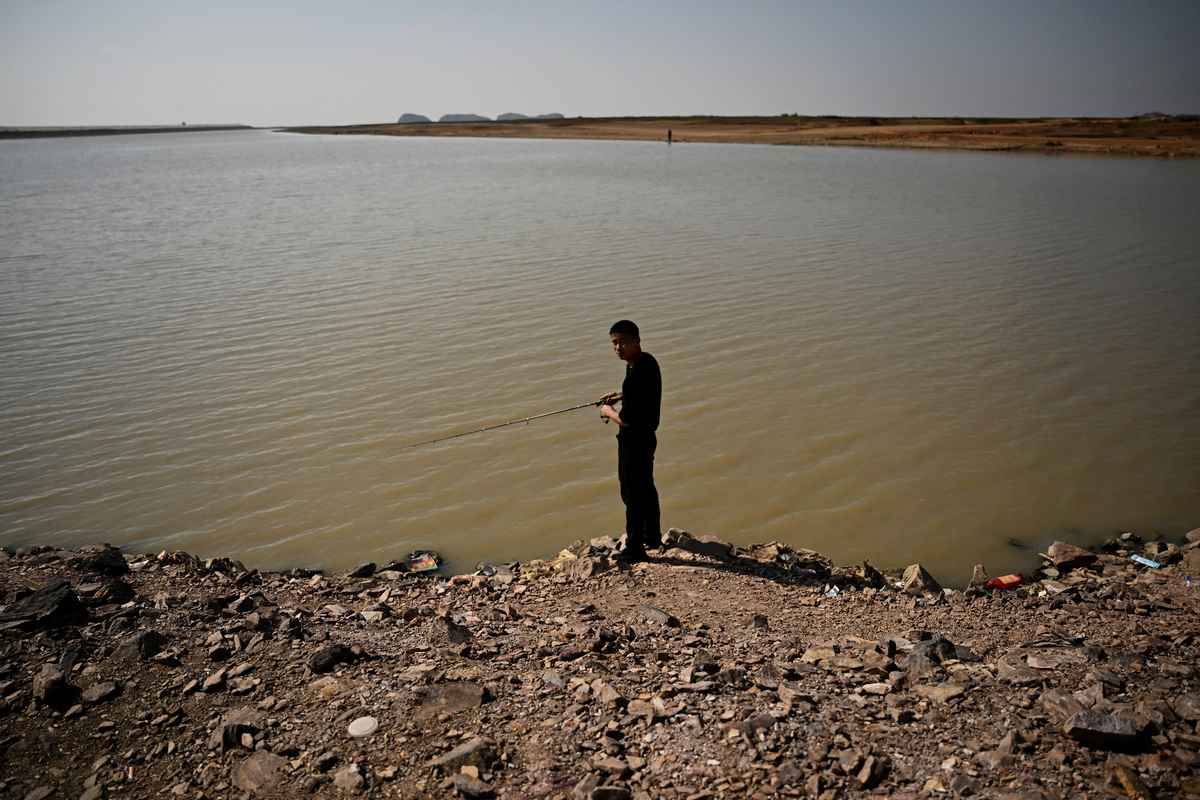 2022年11月7日，一名漁民站在位於江西省九江段的鄱陽湖旁釣魚，湖水已經明顯大幅下降。（Noel CELIS / AFP）