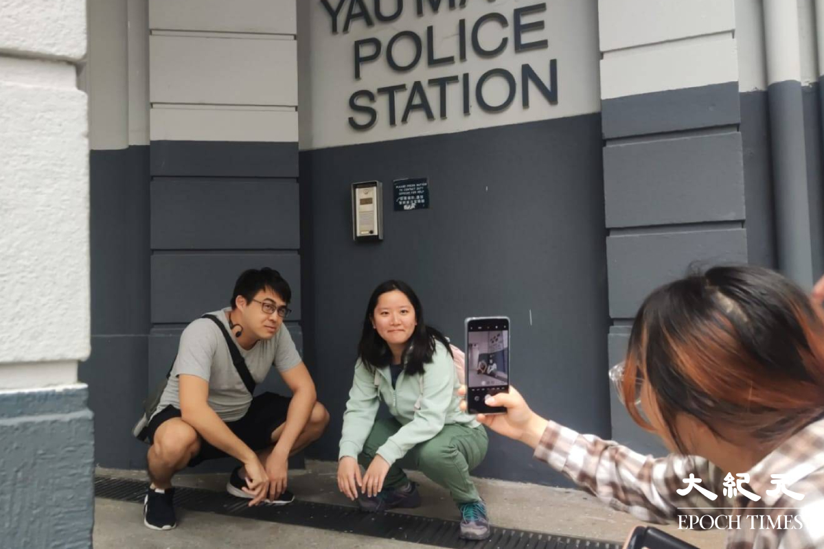 有遊客蹲在警署門前拍照。（鄭兆東／大紀元）