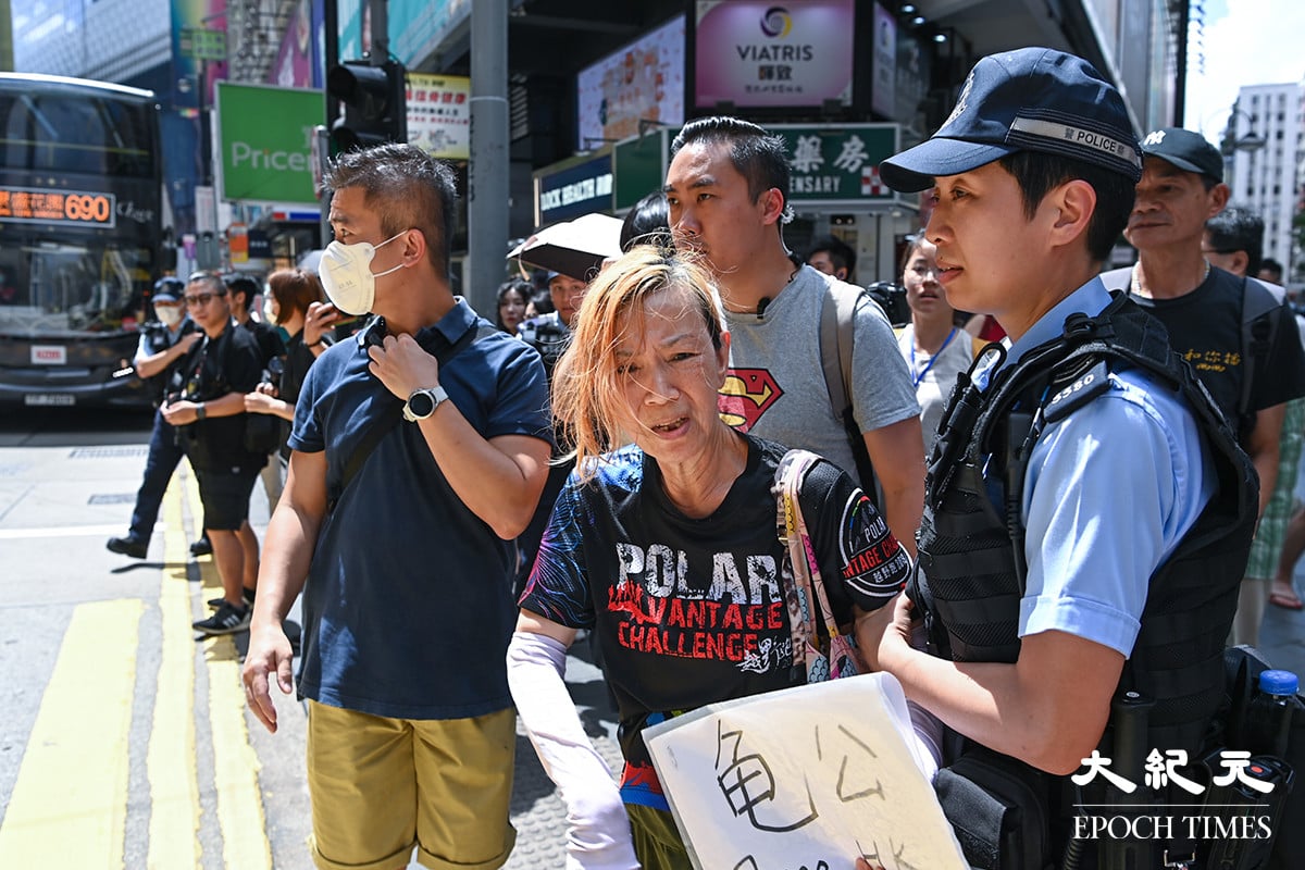 一女子在百德新街手持「龜公 Free Hk」、「公投」兩面標語紙板，被警察拘捕送上警車。（ 宋碧龍／大紀元）