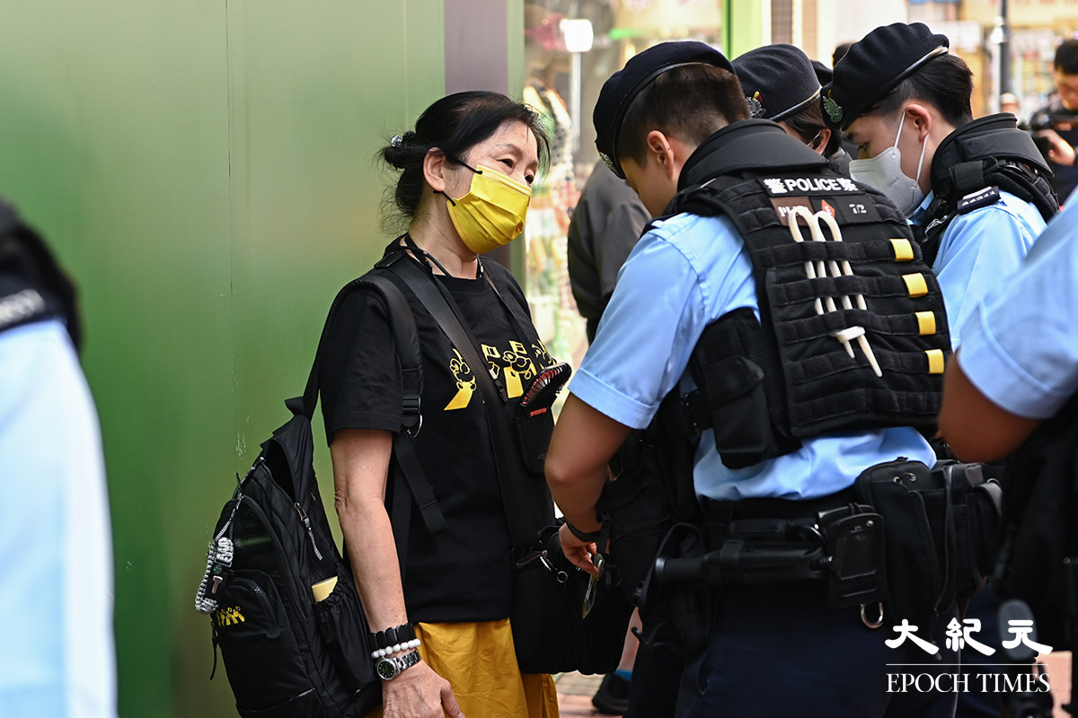戴著黃色口罩的女子被警方截查。（宋碧龍／大紀元）