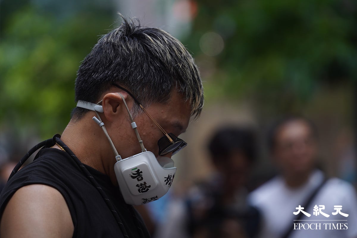 一名身穿黑衣的男子戴著一個白色、寫有「香港加油」的口罩，被警方截查。（劉駿軒／大紀元）