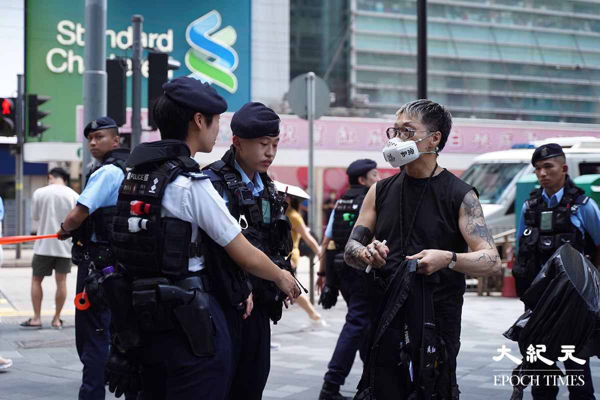 一名身穿黑衣的男子戴著一個白色、寫有「香港加油」的口罩，被警方截查。（劉駿軒／大紀元）
