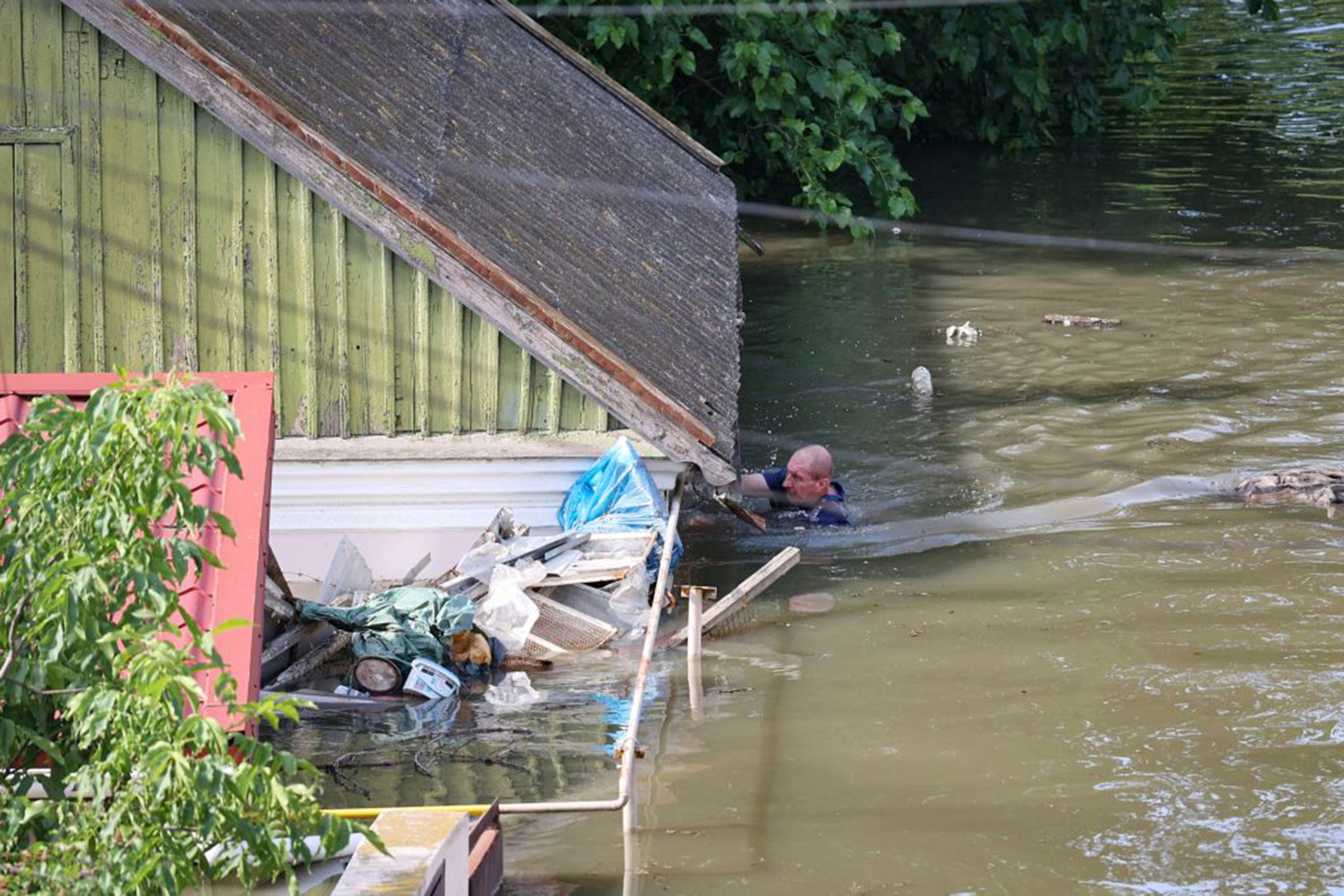 6月7日，一名當地居民在赫爾松市洪水中的房屋旁游水前進。(OLEXANDER KORNYAKOV/AFP via Getty Images)