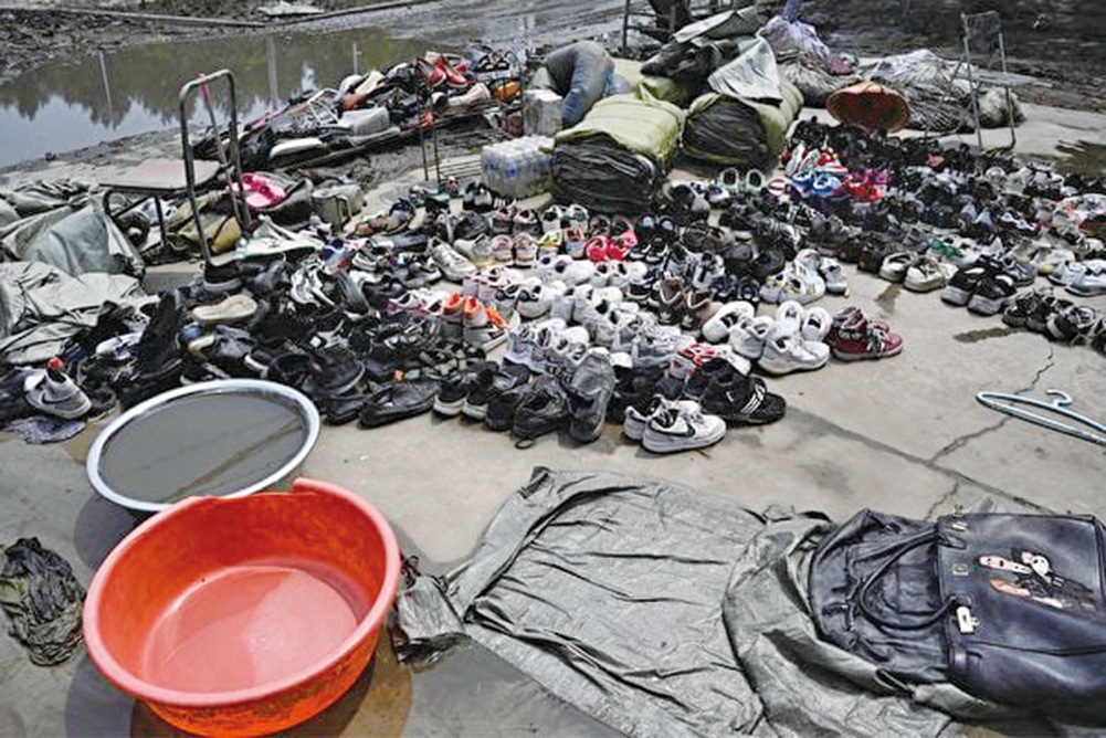 8月9日，河北省涿州市一個村莊因洪災而被淹後，人們把包和鞋子放在倉庫外晾乾。（Jade Gao / AFP）