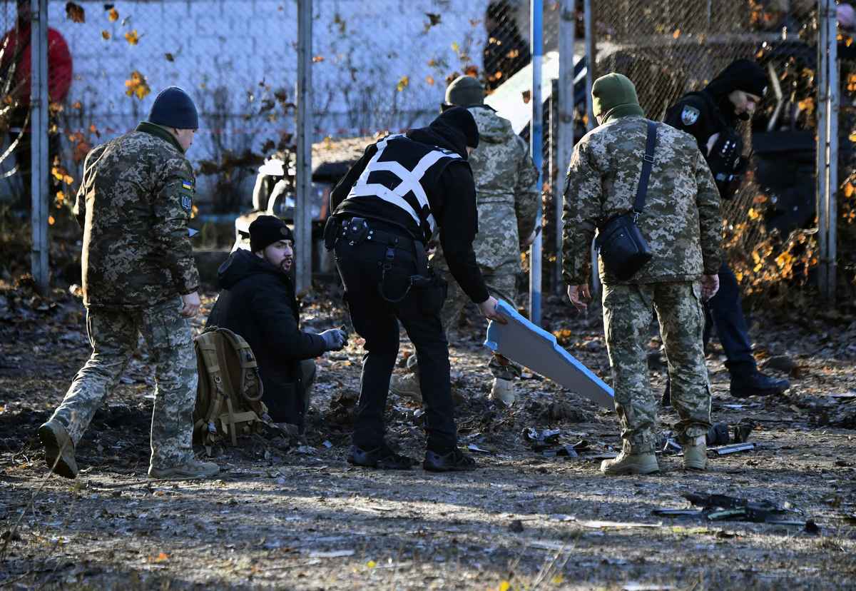 2023年11月25日，烏克蘭警察和軍事專家在基輔的一幢住宅大樓的院子裏的一個彈坑周圍收集被擊落的俄羅斯無人機碎片。（Sergei SUPINSKY / AFP）