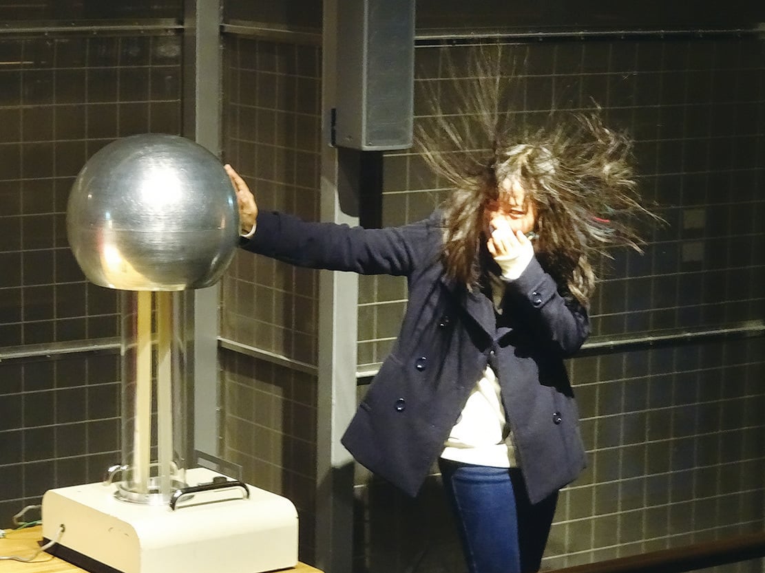 放電室中女孩手放在電球上後頭髮就因靜電作用而豎起來了。（王知涵／大紀元）