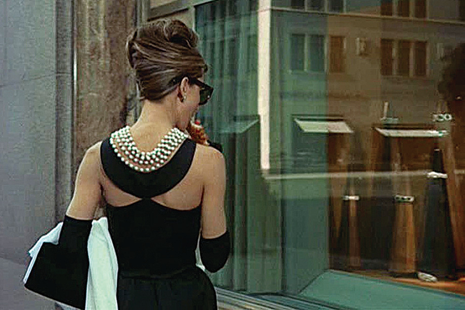 《珠光寶氣》劇照。清晨時分，柯德莉夏萍站在Tiffany珠寶店的窗前，盯著能給她帶來快樂和安全感的美麗櫥窗。那一刻我們其實想要的不是小黑裙，而是柯德莉夏萍。她所詮釋的Holly Golightly與你我是如此的接近。人性中的共鳴為一件衣服賦予了無窮的魅力。（網絡圖片）