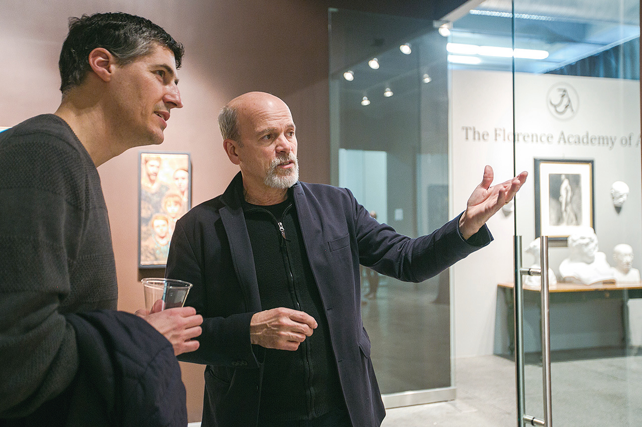 2016年5月1日，在佛羅倫斯美術學院畫廊的「Consecrated Reality」（聖潔的現實）藝術展覽開幕式上，該院創始人丹尼爾‧格雷夫斯（右）與藝術家愛德華‧米諾夫（Edward Minoff）在討論一張繪畫。（Milene Fernandez/Epoch Times）
