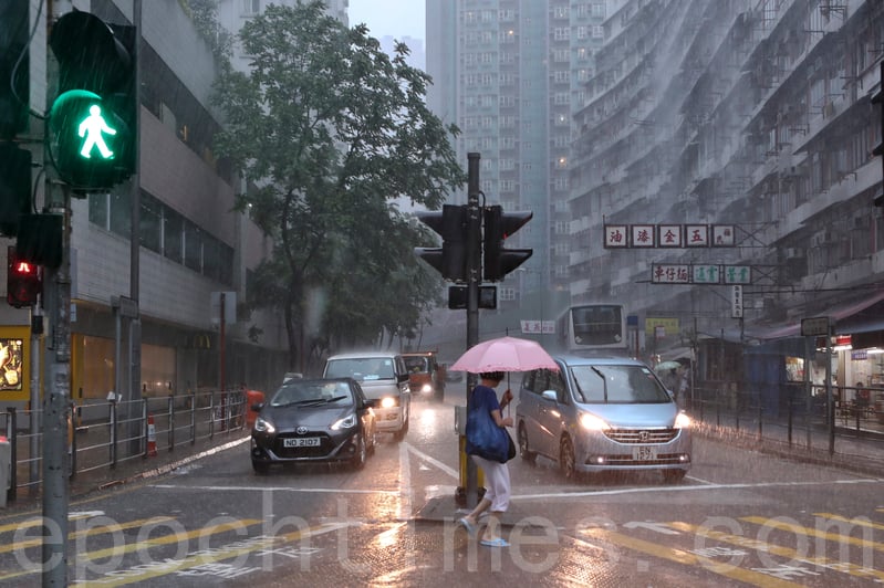 5月24日上午，香港天氣驟變，天文台在上午11時30分發出黑色暴雨警告信號。圖為暴雨下街上的途人。（余鋼／大紀元）