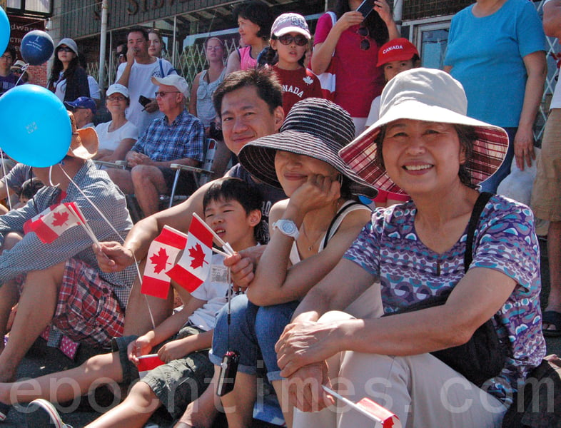 圖為香港移民Peter Ng一家開心地觀看列治文國慶遊行，慶賀加拿大國慶節。（邱晨／大紀元）