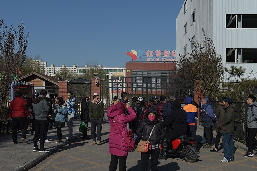 近日，北京發生的兩個大事件——北京清查逼遣大批外來人員與紅黃藍幼兒園虐童案。圖為家長在向媒體曝光紅黃藍幼兒園虐待、猥褻孩子的真相。（NICOLAS ASFOURI/AFP/Getty Images）