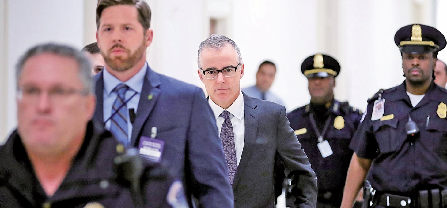 去年12月21日，FBI副局長麥凱布（戴眼鏡者）在警員陪同下前往美國眾議員辦公的瑞本大樓。（Getty Images）