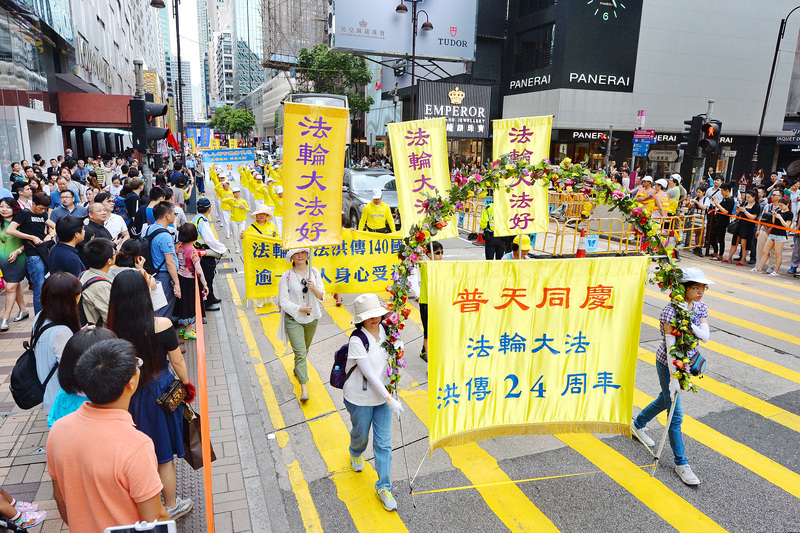 來自各地和香港的部份法輪功學員，在長沙灣舉行恭祝李洪志大師華誕及慶祝世界法輪大法日遊行。圖為遊行經過鬧區吸引許多民眾觀看。（宋祥龍/大紀元）