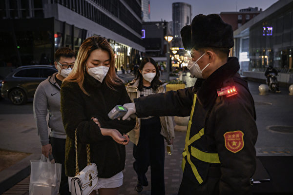 2020年3月14日，北京一名婦女在接受保安人員檢查體溫。（Kevin Frayer/Getty Images）