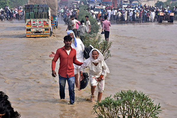 2021年10月20日，印度北方邦（Uttar Pradesh）蘭普爾（Rampur）附近，豪雨導致科西河（Kosi river）氾濫，民眾涉水通行。（AFP via Getty Images）