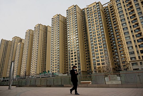 圖為2021年12月8日，一名男子走過中國房地產開發商恒大在北京的住宅區。（Noel Celis / AFP）