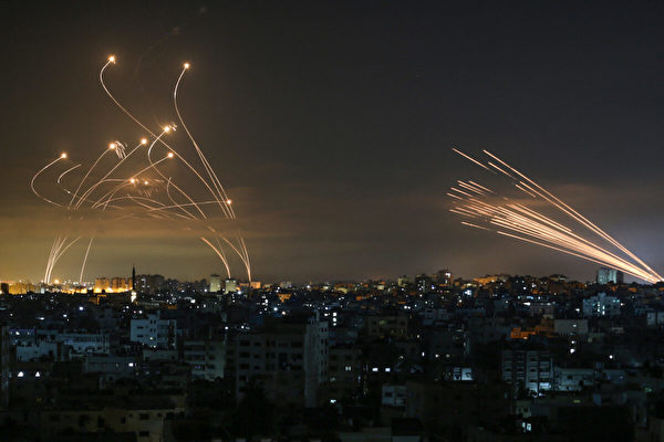 2021年5月14日夜間，從加沙地帶上空看到，以色列的鐵穹導彈防禦系統（Iron Dome，左）在攔截哈馬斯（Hamas）從加沙地帶北部拜特‧拉希耶（Beit Lahia）向以色列南部發射的火箭炮（右）。（ANAS BABA/AFP via Getty Images）