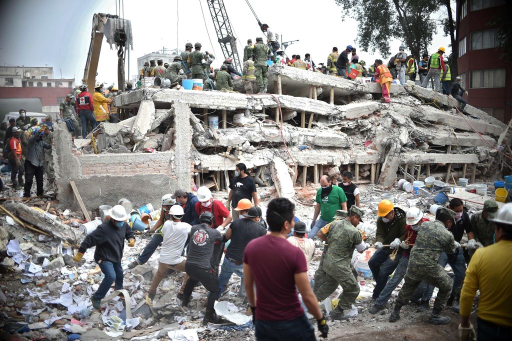 在兩次毀滅性地震的周年紀念日，墨西哥再次發生強震。圖為2017年9月20日，在墨西哥中部發生強烈地震後的一天，救援人員在墨西哥城一座夷為平地的建築物中尋找倖存者。（Yuri Cortez/AFP via Getty Images）