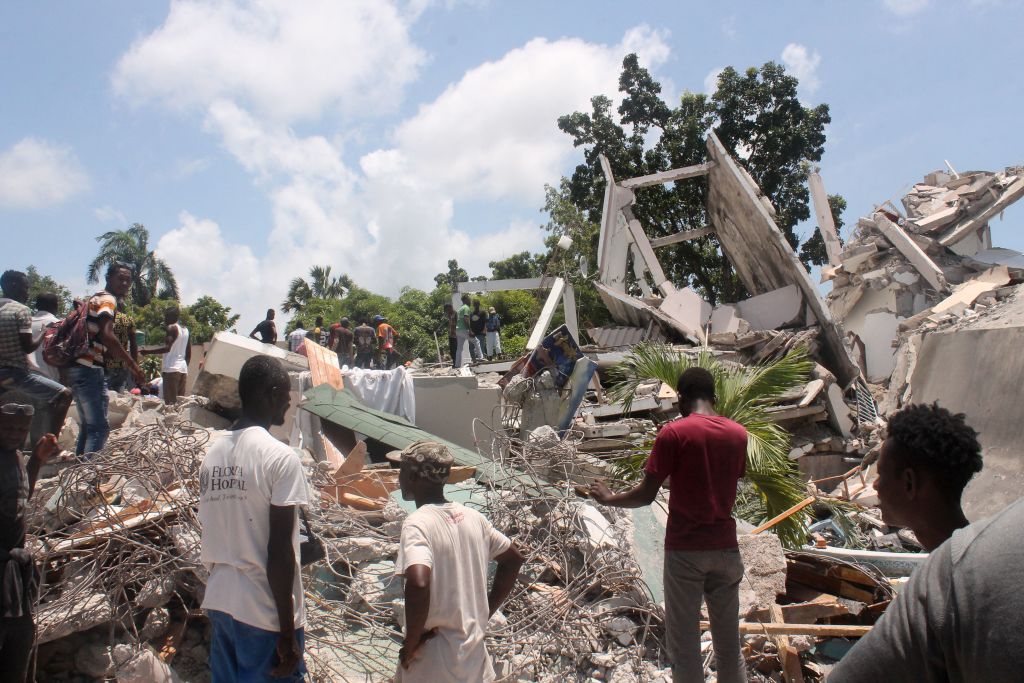 海地2021年8月14日發生7.2級大地震，目前已造成至少1297人死亡。圖為2021年8月14日，海地萊凱（Les Cayes）發生地震後，人們在廢墟中搜尋倖存者。（STANLEY LOUIS/AFP via Getty Images）