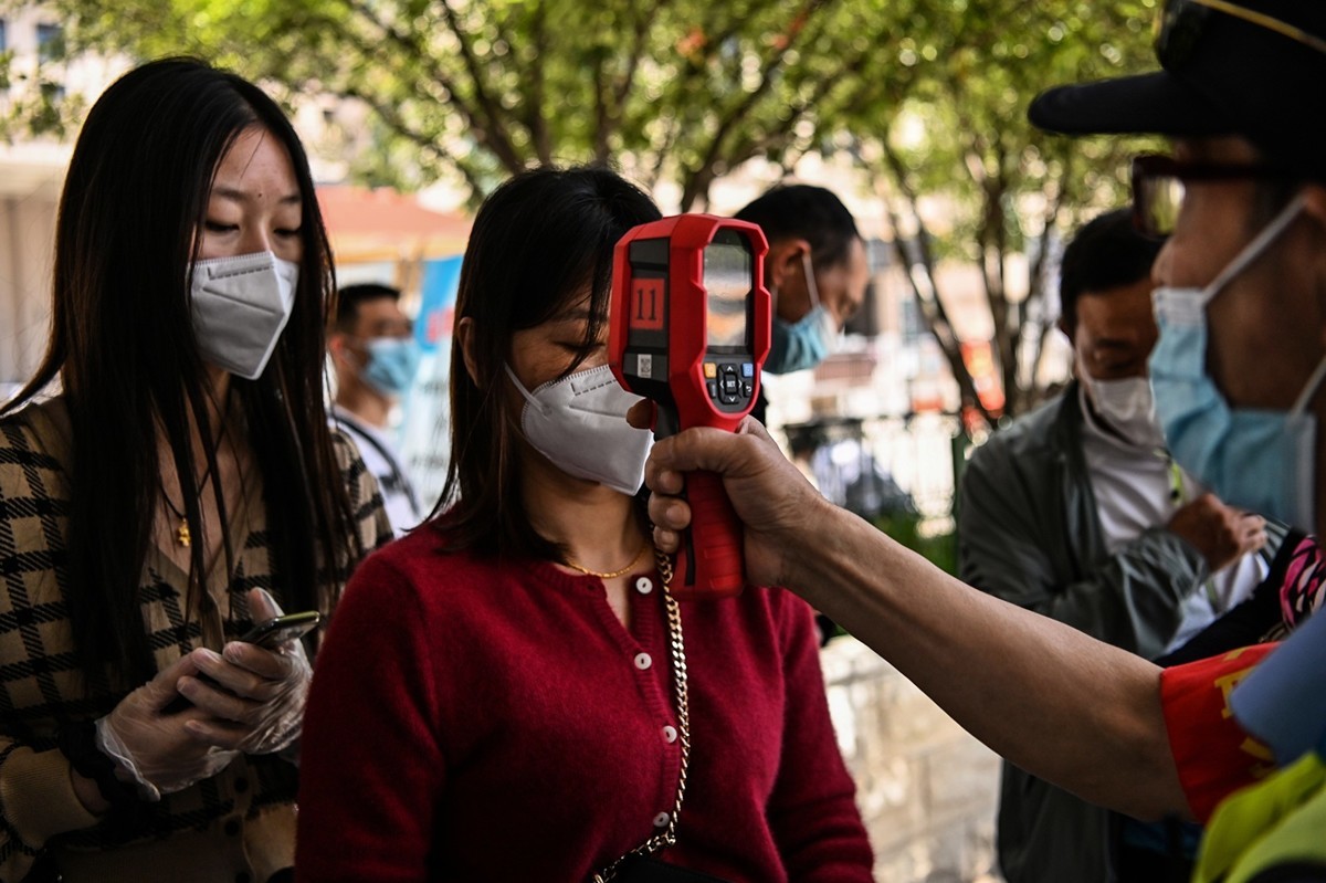 中國東北地區近期成為疫情重災區。圖為5月12日武漢火車站工作人員在檢查乘客的體溫。（AFP/Getty Images）