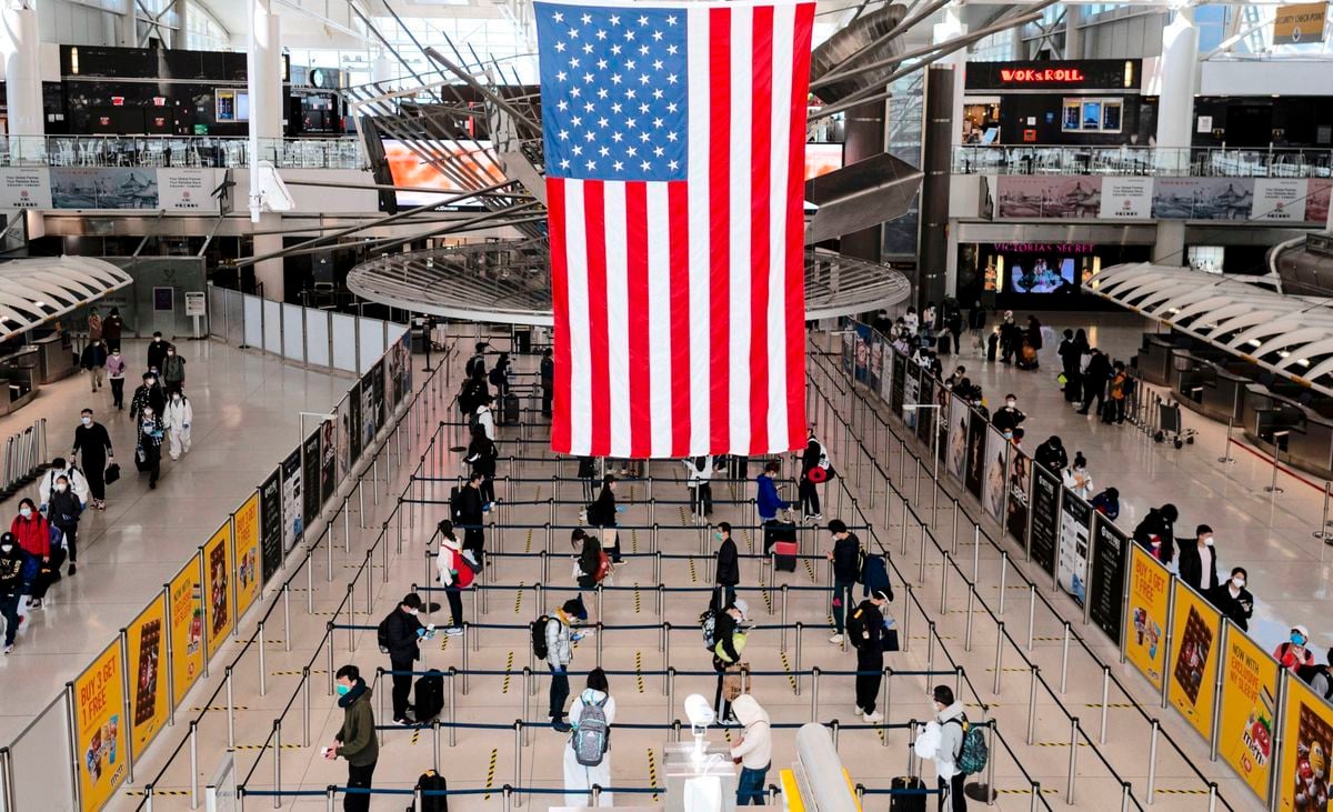 圖為2020年5月13日，穿戴著口罩和防護裝備的旅客在紐約市甘迺迪機場1號航站樓排隊等候出關。（JOHANNES EISELE/AFP via Getty Images）