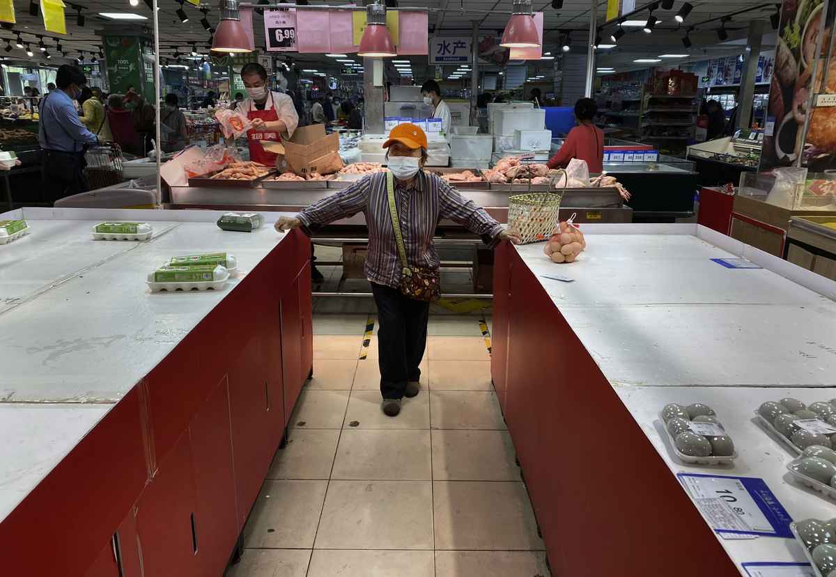 2022年4月25日，在北京朝陽區的一家超市，一名婦女站在幾乎雞蛋都被完後，空蕩蕩的貨架之間。（Kevin Frayer/Getty Images）