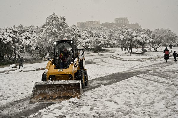 2022年1月24日，希臘雅典，衛城（Acropolis）附近白雪紛飛，一輛鏟雪車行駛於道路上。（Louisa Gouliamaki/AFP）
