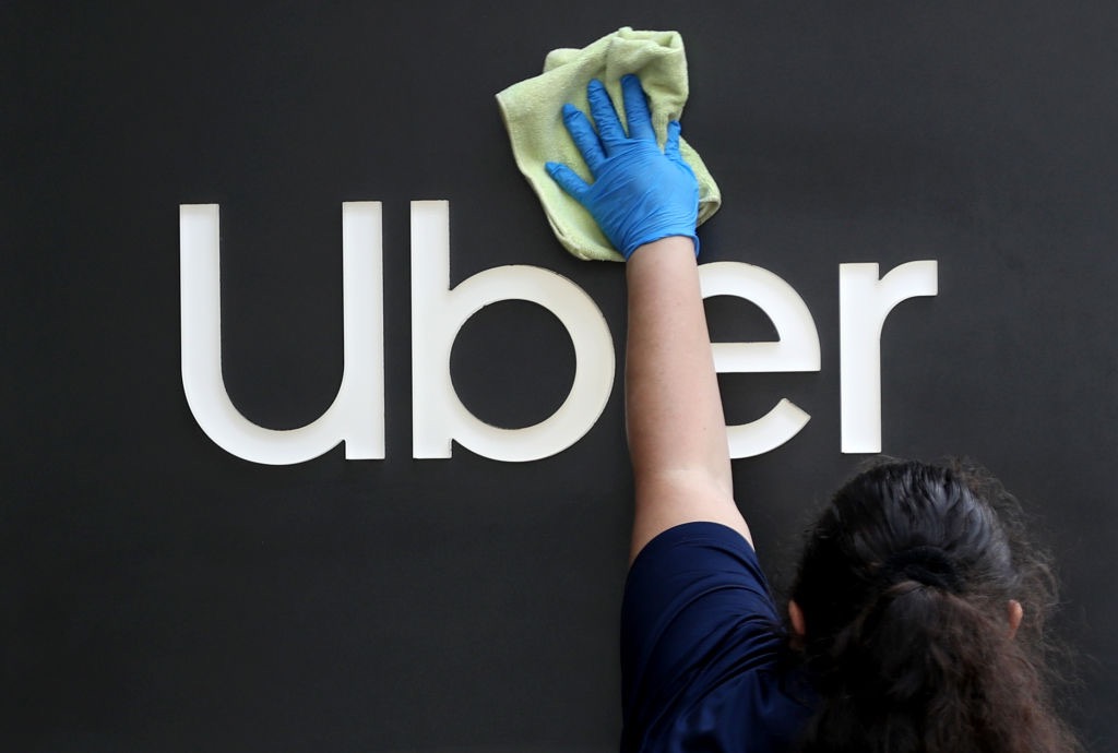 圖為2020年5月18日，在加州三藩市，一名工人在清潔Uber公司總部前的標誌。（Justin Sullivan/Getty Images）