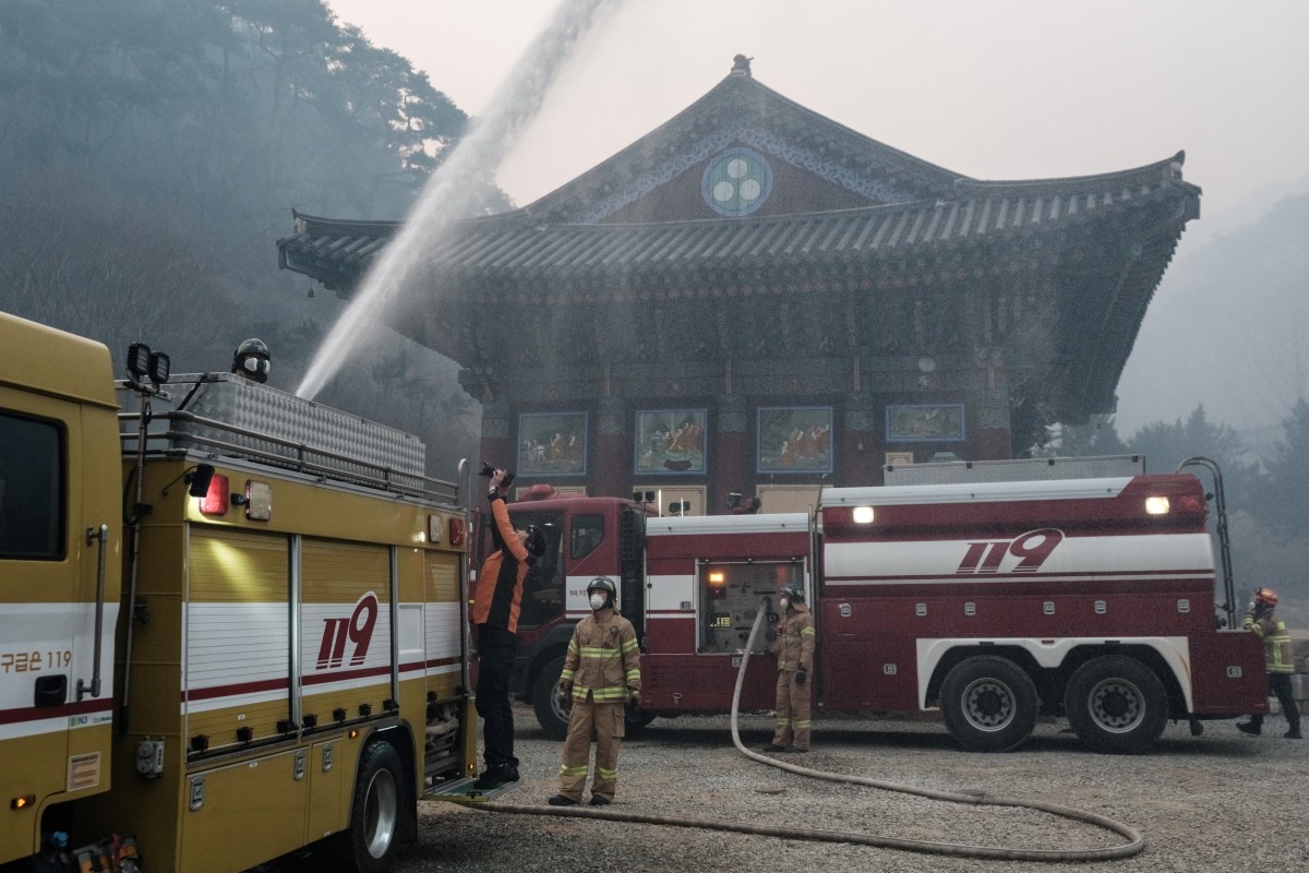 一名消防員於2025年3月26日,在慶尚北道義城的高雲寺(Gounsa Temple)操作消防車水砲,試圖撲滅殘餘的火勢。(YASUYOSHI CHIBA/AFP)