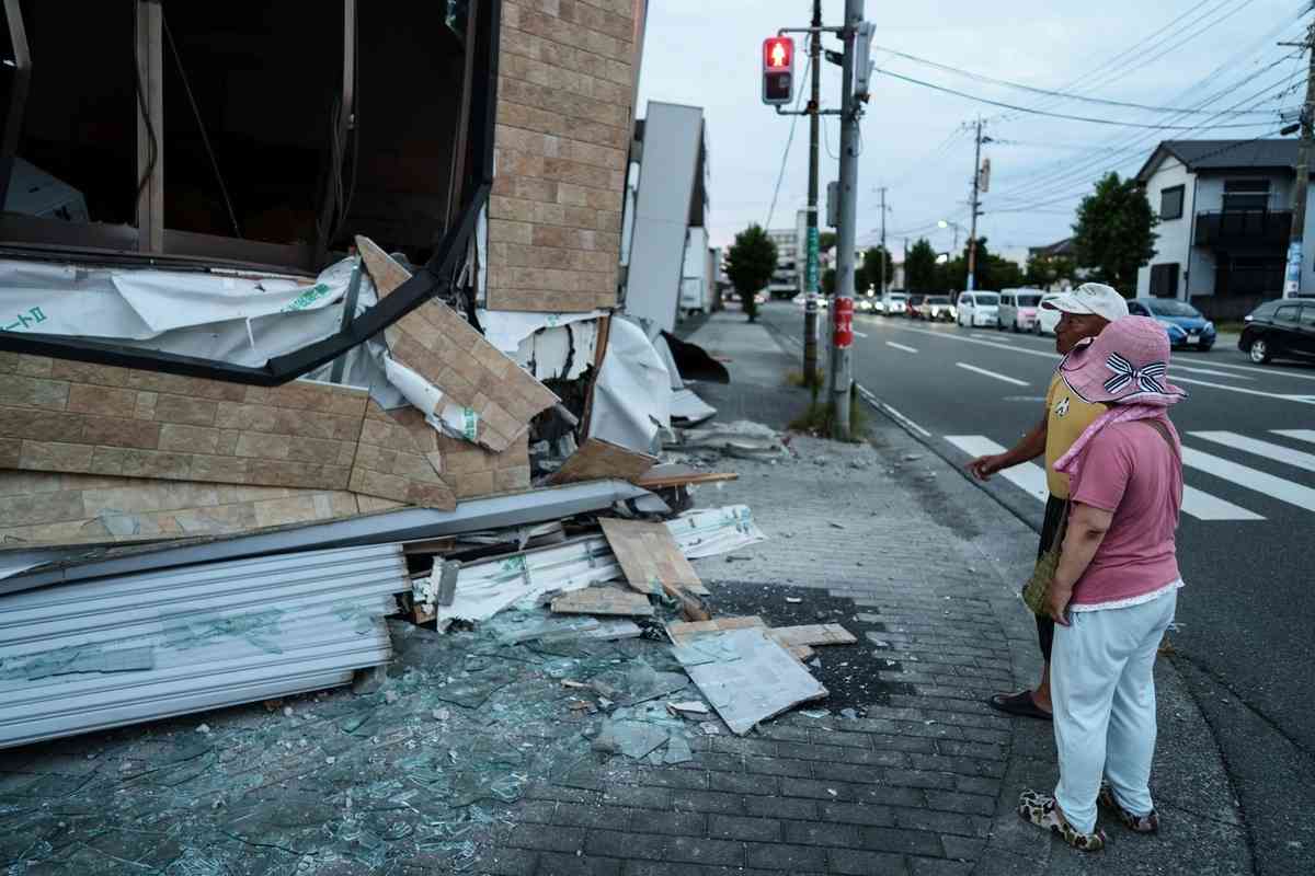 2026年7月29日，日本熊本縣八代市，一對夫婦看著一棟在地震中受損的建築。（Tomohiro Ohsumi/Getty Images）