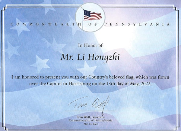 賓夕凡尼亞州州長湯姆沃爾夫（Tom Wolf）頒發證書，將這面5.13飄揚在賓夕凡尼亞州國會大廈的美國國旗贈送給李洪志先生。（李臻婷／大紀元）