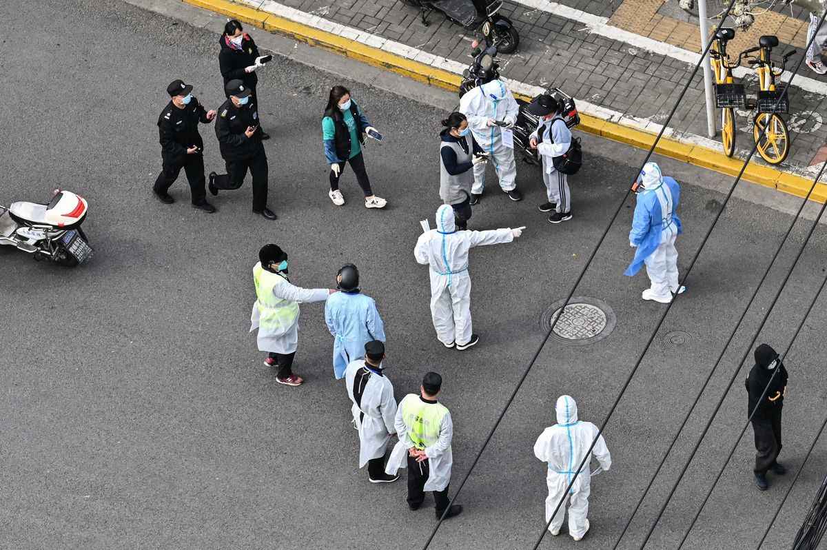 2022年4月1日，在上海靜安區COVID-19封鎖的第二階段，穿著個人防護裝備的人向街上的居民打手勢。（Hector Retamal/AFP via Getty Images）
